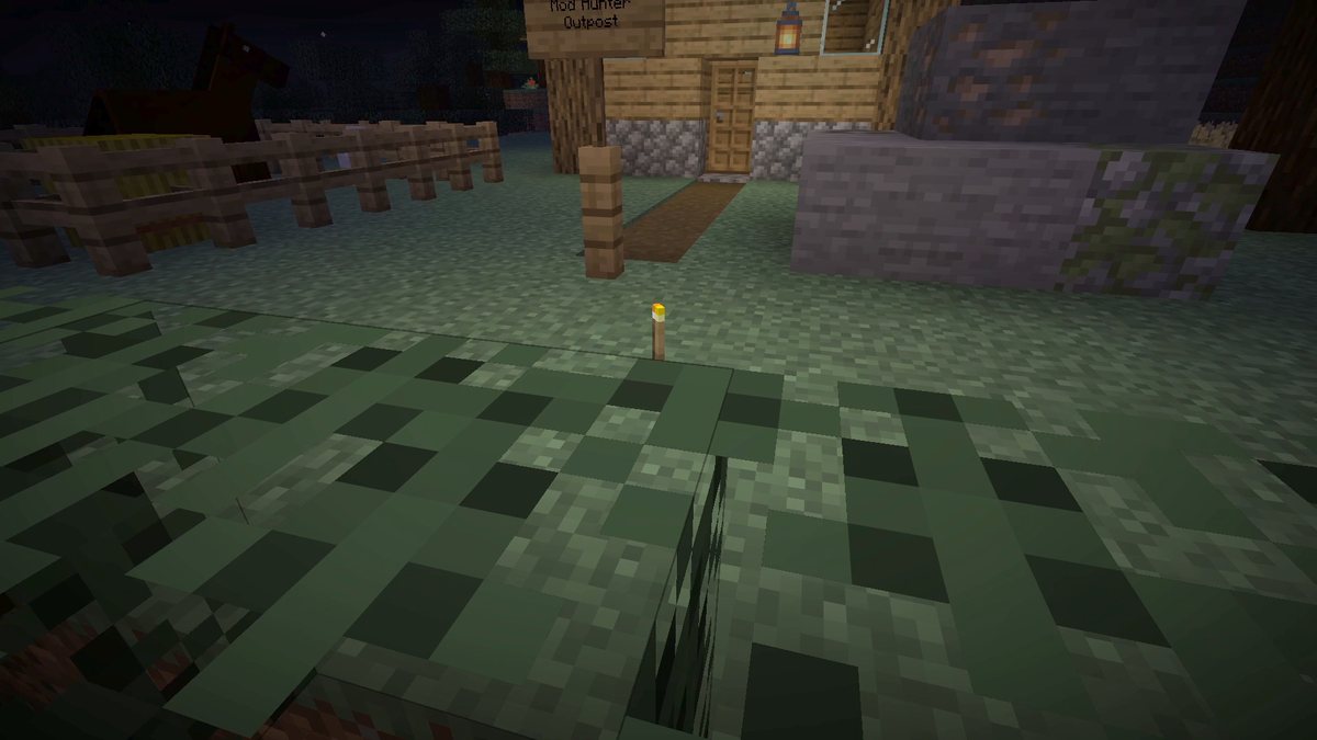 Minecraft screenshot at night of a dropped torch item on the grass with a small circle of light around it